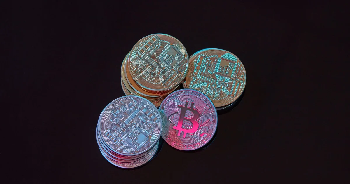 Monedas de bitcoin y un candado digital roto sobre un teclado