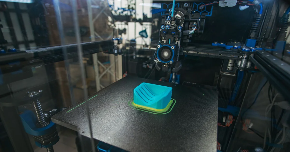 Primer plano de una impresora 3D fabricando una pieza plástica en un entorno industrial