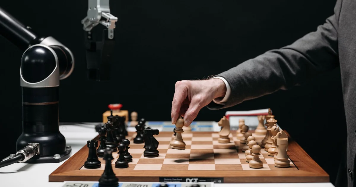 Brazo robótico jugando ajedrez contra una persona, símbolo de la innovación en inteligencia artificial